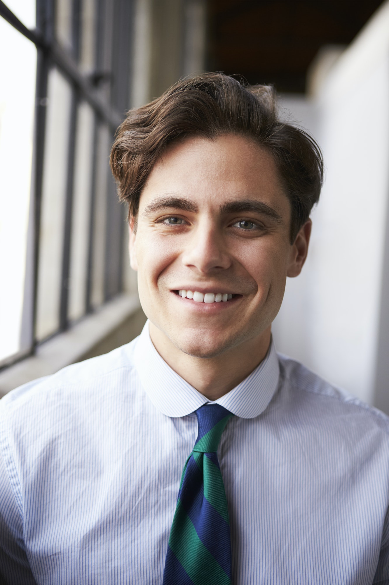 Young white businessman smiling, vertical portrait